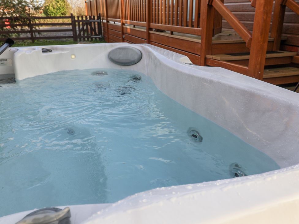 A hot tub filled with water on a deck at Fern Lodge in Stonham Aspal