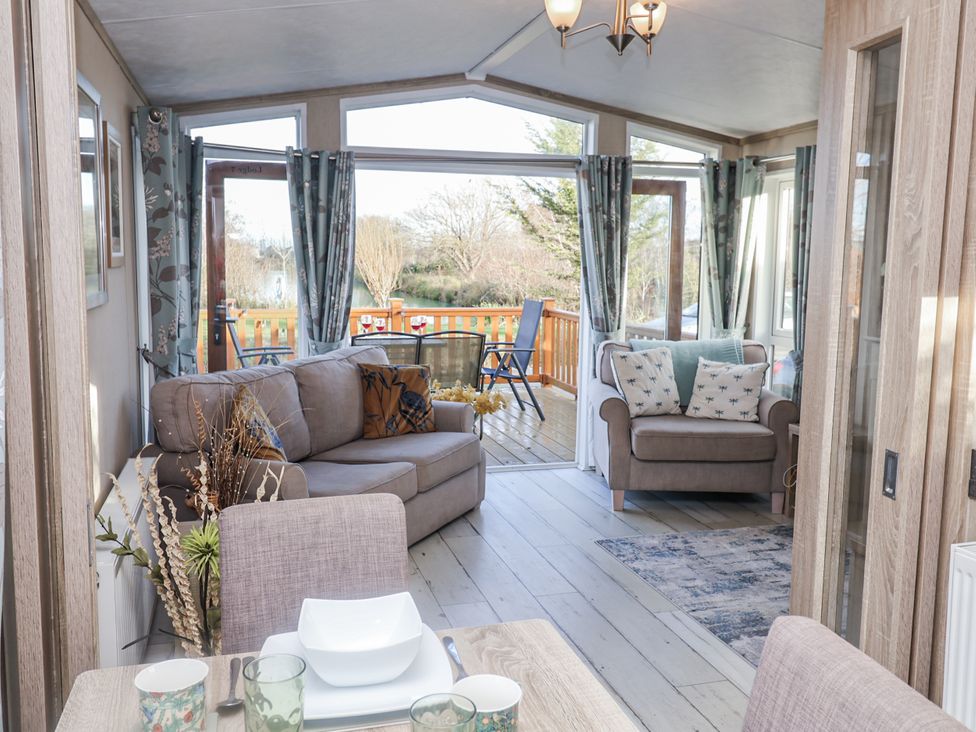 A living room with sofa and chairs overlooking a deck at Fern Lodge in Stonham Aspal