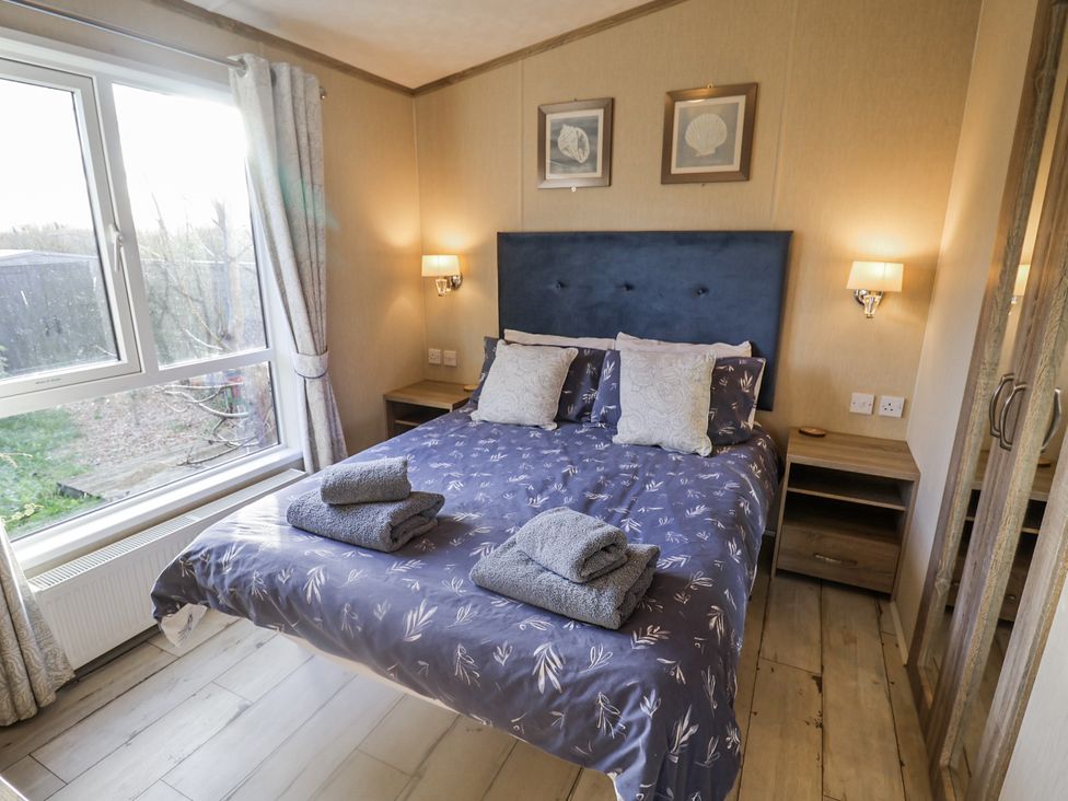 A bedroom with a bed and bedside table at Fern Lodge in Stonham Aspal