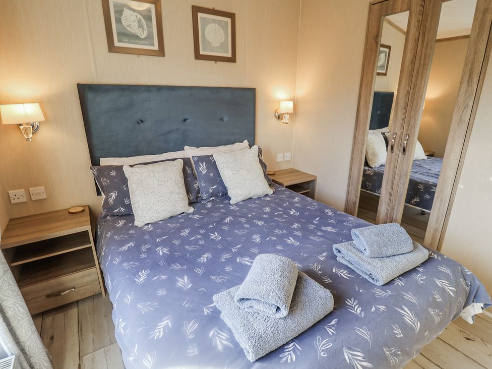 A bedroom with a double bed and towels at Fern Lodge in Stonham Aspal