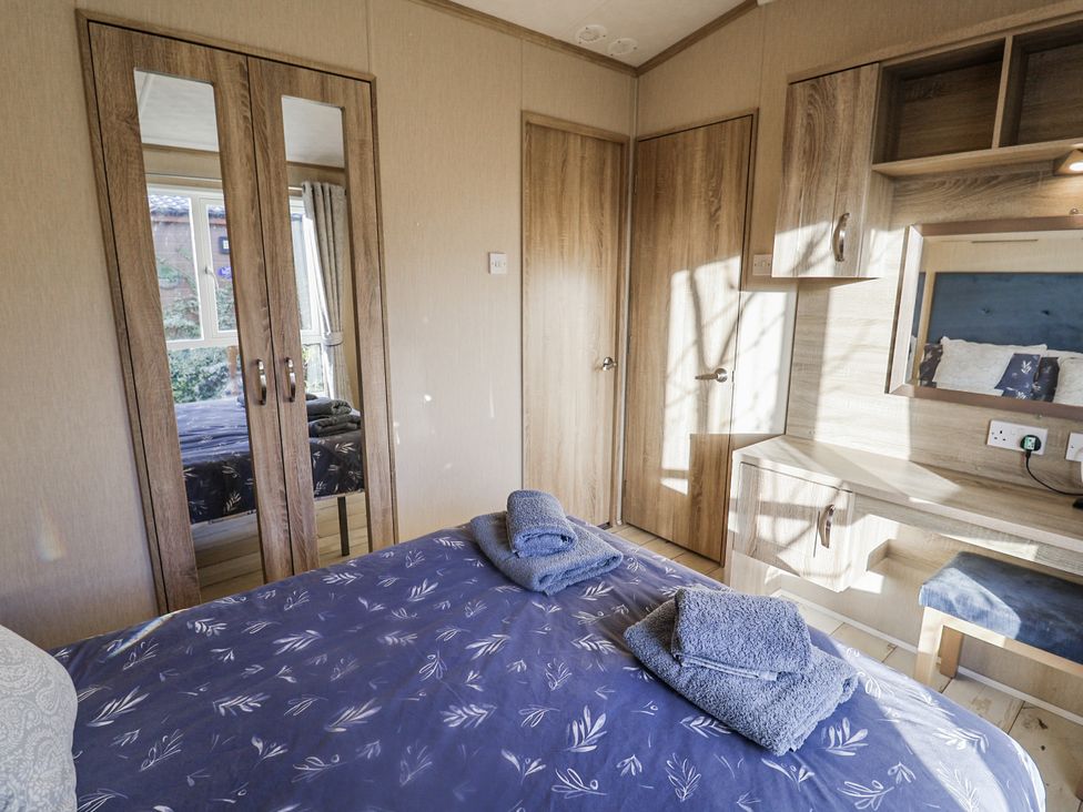 A bedroom with a bed and dresser at Fern Lodge in Stonham Aspal