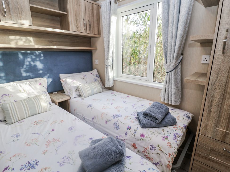 A bedroom with two beds and a window at Fern Lodge in Stonham Aspal