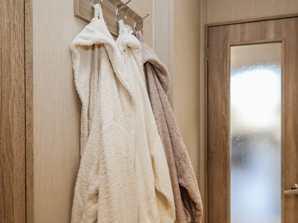 A bathroom with bath robes hanging on hooks at Fern Lodge in Stonham Aspal