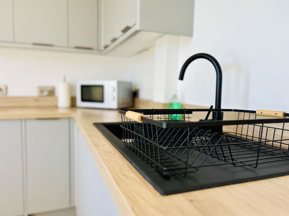 A kitchen with a sink and microwave at 2A Hamilton Road in Felixstowe