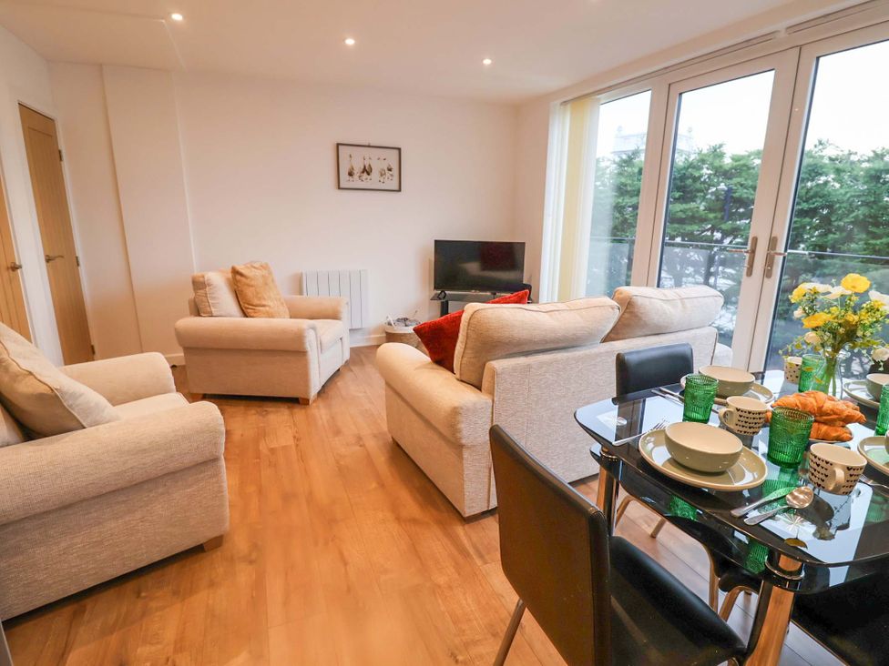 A living room with a television and dining table at Stylish Felixstowe Apartment with Fabulous Sea Views, Felixstowe, Suffolk