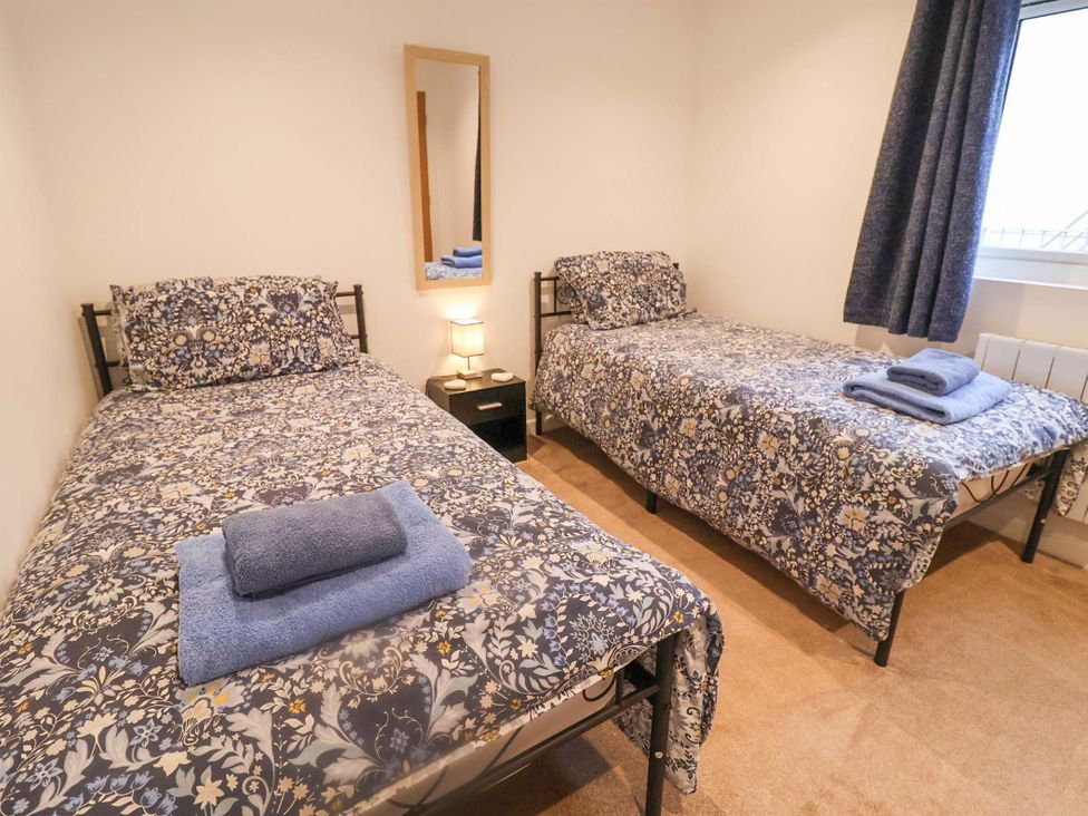 A bedroom with two beds and a bedside table at Stylish Felixstowe Apartment with Fabulous Sea Views in Felixstowe, Suffolk