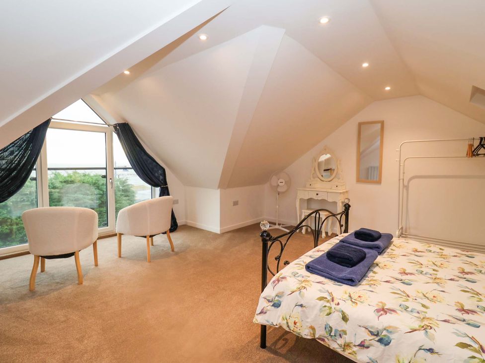 A bedroom with a bed, chairs, and dresser at Stylish Felixstowe Apartment with Fabulous Sea Views, Felixstowe, Suffolk