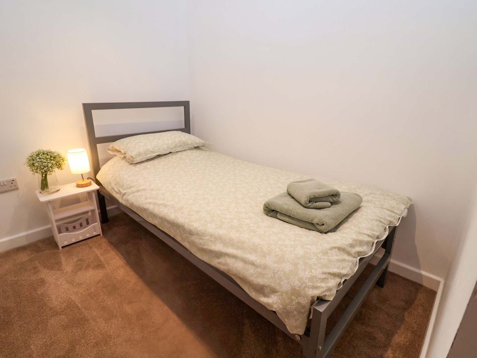 A bedroom with a single bed and a nightstand at Stylish Felixstowe Apartment with Fabulous Sea Views, Felixstowe, Suffolk