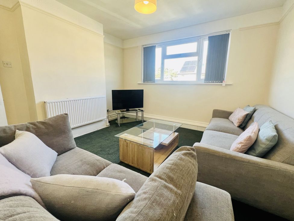 A living room with a sofa, coffee table, and TV at 11 Langer Road in Felixstowe