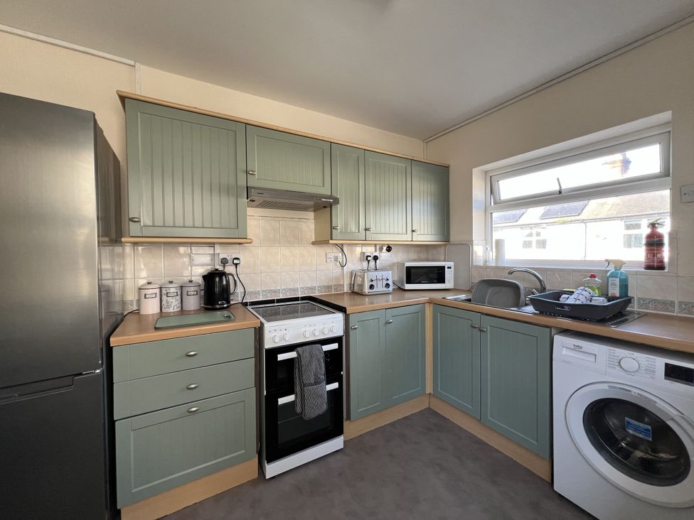 A kitchen with appliances including a fridge, oven, and washing machine at 11 Langer Road in Felixstowe
