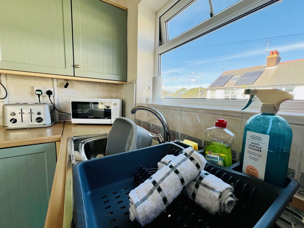 A kitchen with a sink, microwave, and cleaning supplies at 11 Langer Road, Felixstowe
