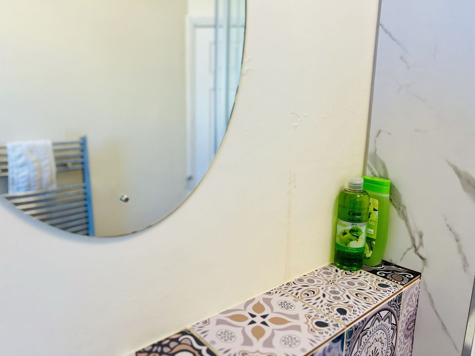 A bathroom with a mirror and shelf holding shower gel at 11 Langer Road Felixstowe
