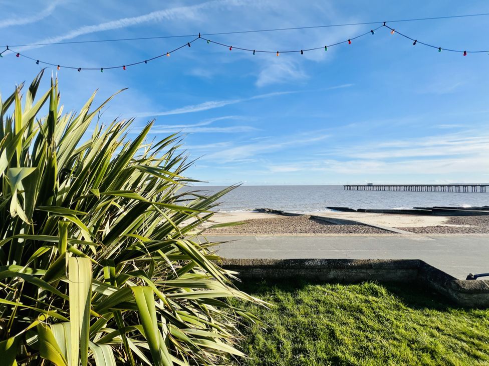 A view of the beach with a pier and plants at 11 Langer Road in Felixstowe