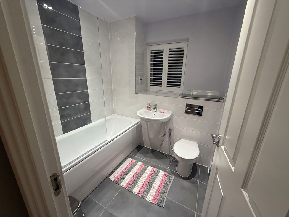 A bathroom with a bath tub toilet and sink at 14 Becket Close Woodford Green
