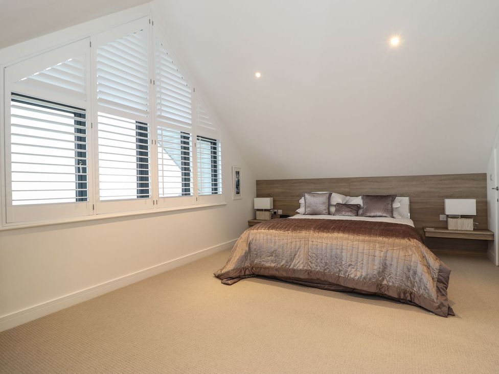 A bedroom with a bed and windows at Praa Waves in Penzance