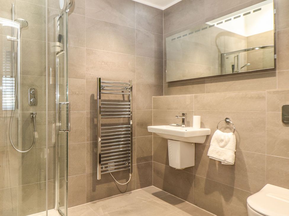 A bathroom with shower, sink, toilet and towel rail at Praa Waves in Penzance