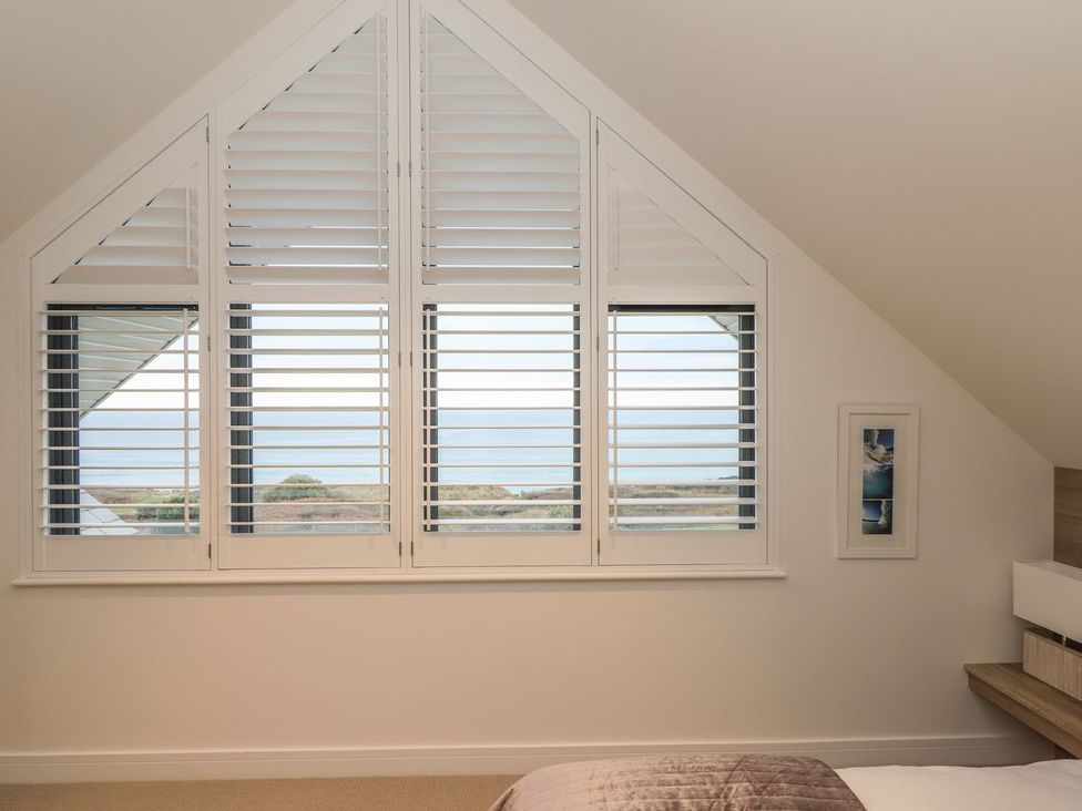 A bedroom with a window and shutters at Praa Waves in Penzance
