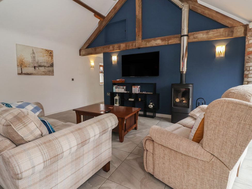 A living room with a fireplace and tv at Pillar Barn in Driffield