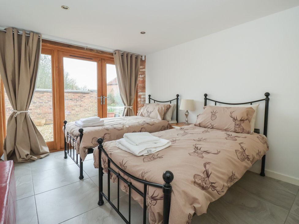 A bedroom with two beds and sliding doors at Pillar Barn Driffield