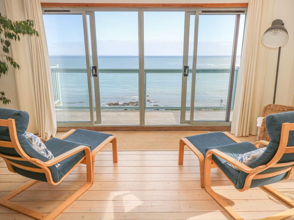 A living room with chairs and a sea view at Harbour Lights in Penzance