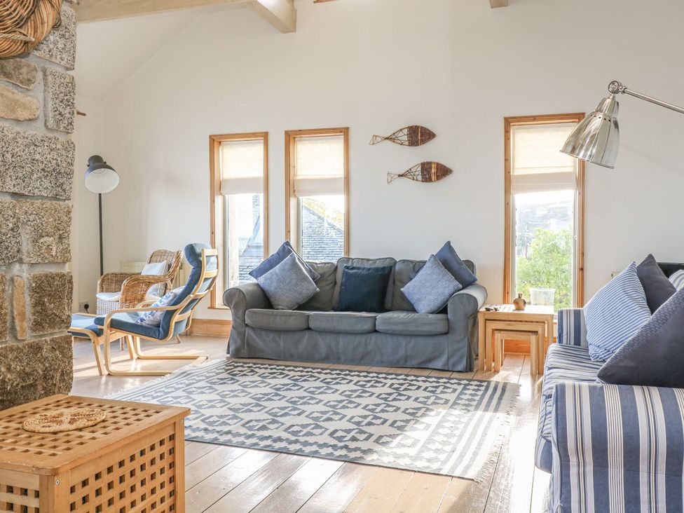 A living room with sofa, chairs and windows at Harbour Lights in Penzance