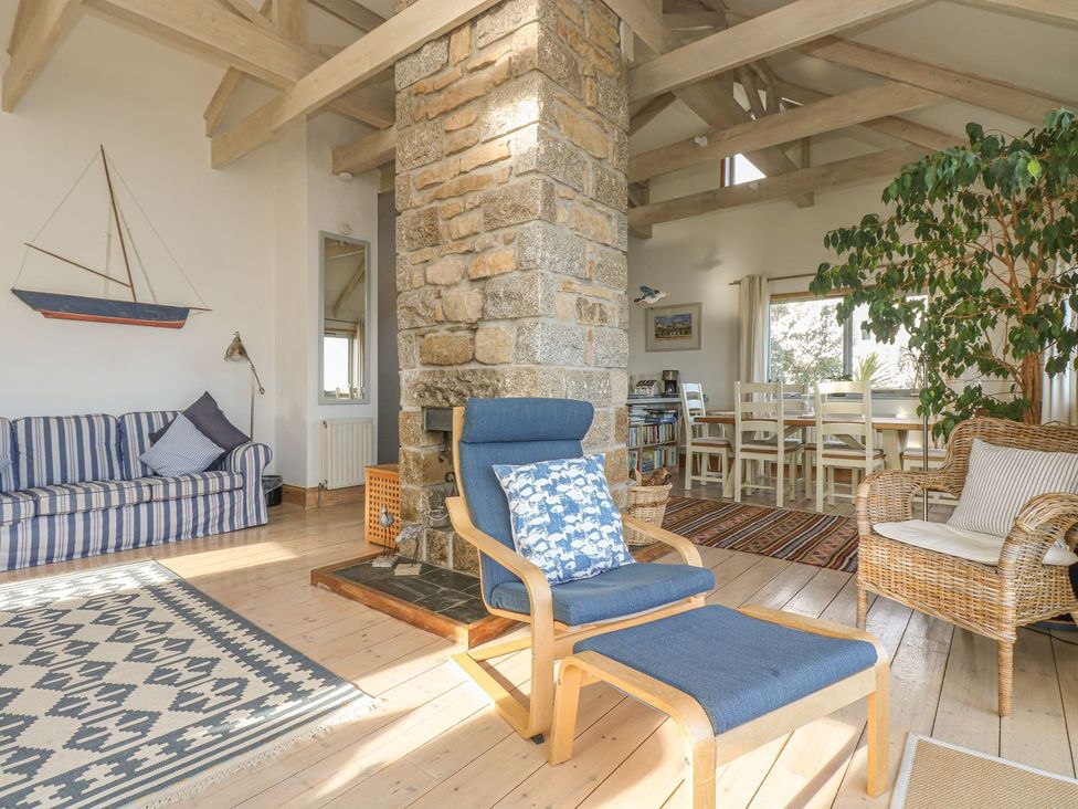 A living room with a stone chimney and dining area at Harbour Lights in Penzance