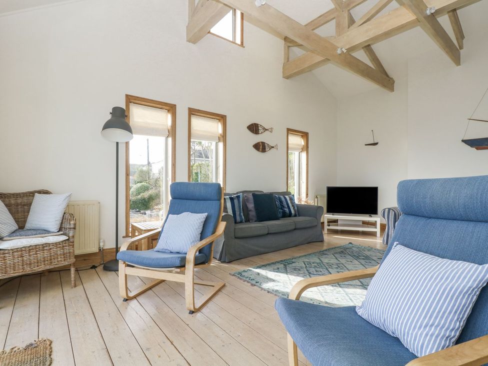 A living room with a sofa and two armchairs at Harbour Lights in Penzance