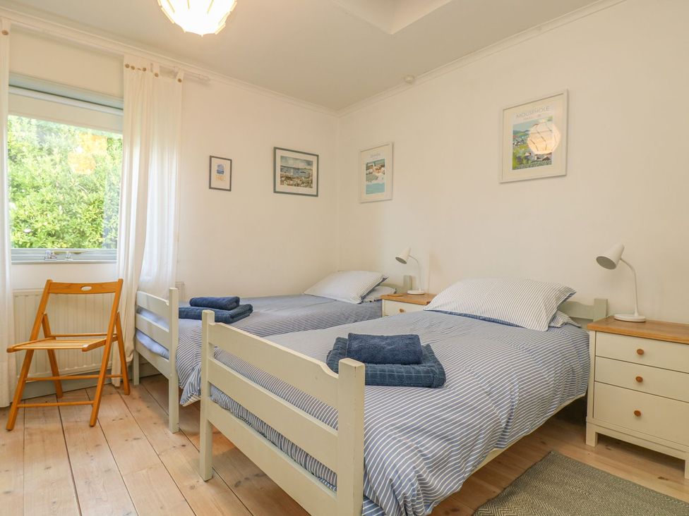 A bedroom with two beds and a chair at Harbour Lights in Penzance