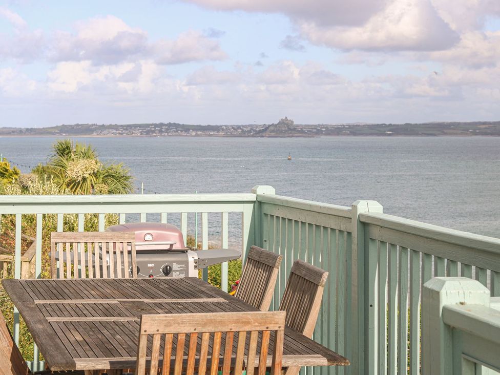An outdoor deck with a table and chairs and a barbecue at Harbour Lights in Penzance