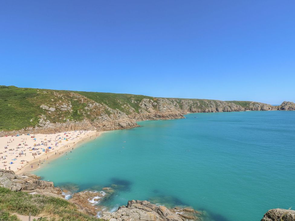 A beach with people and clear water at Harbour Lights in Penzance