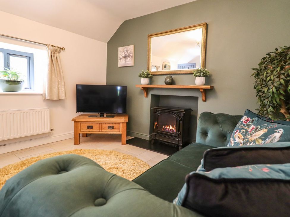 A living room with a fireplace and television at The Talkhouse Cottage in Caersws