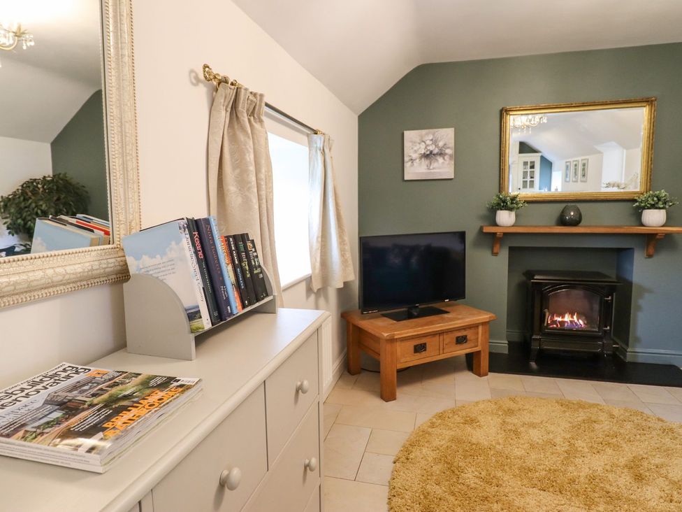 A living room with a television and fireplace at The Talkhouse Cottage in Caersws