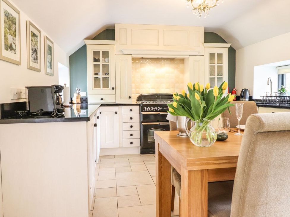 A kitchen with a table and chairs at The Talkhouse Cottage Caersws