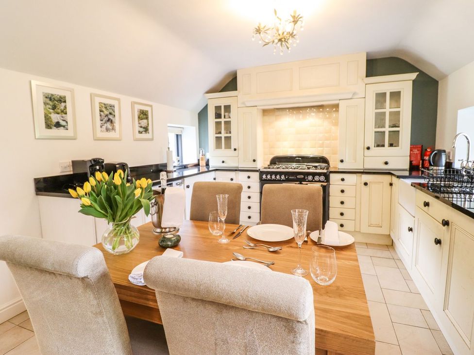 A kitchen with a dining table and flowers at The Talkhouse Cottage in Caersws