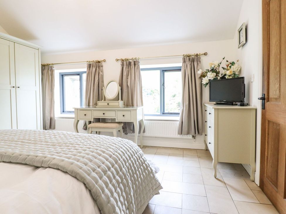 A bedroom with a bed and dresser at The Talkhouse Cottage in Caersws