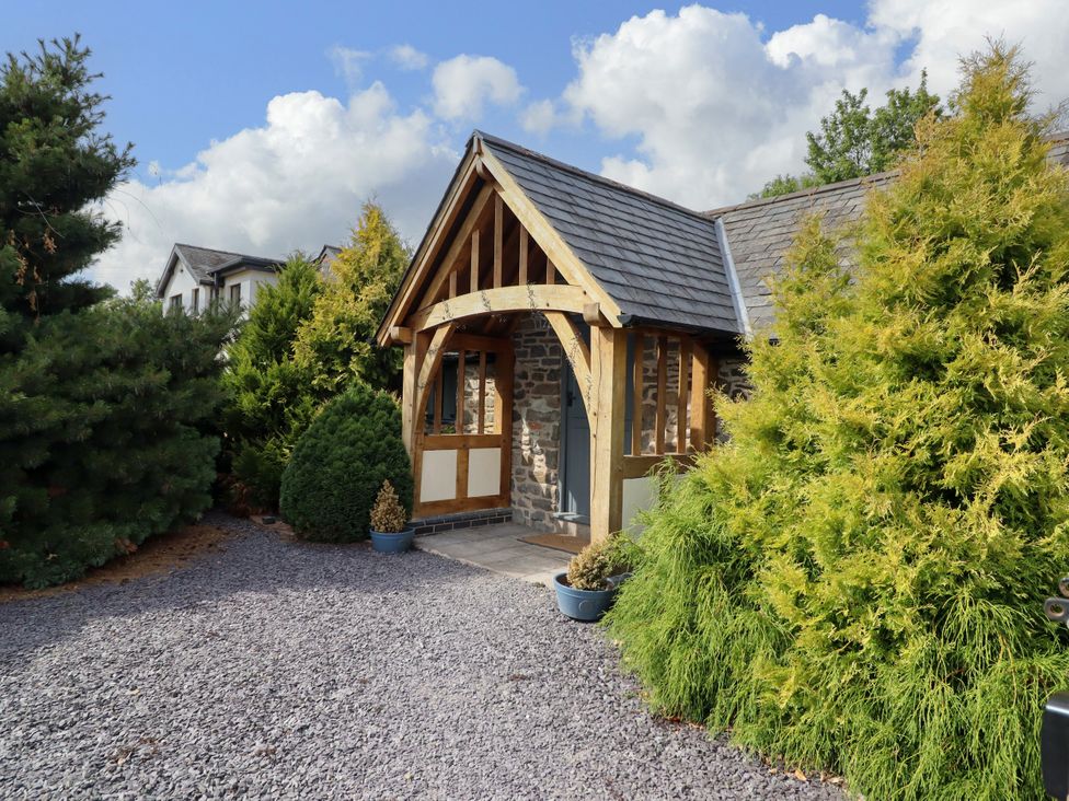 A house with a front door and window surrounded by bushes at The Talkhouse Cottage Caersws