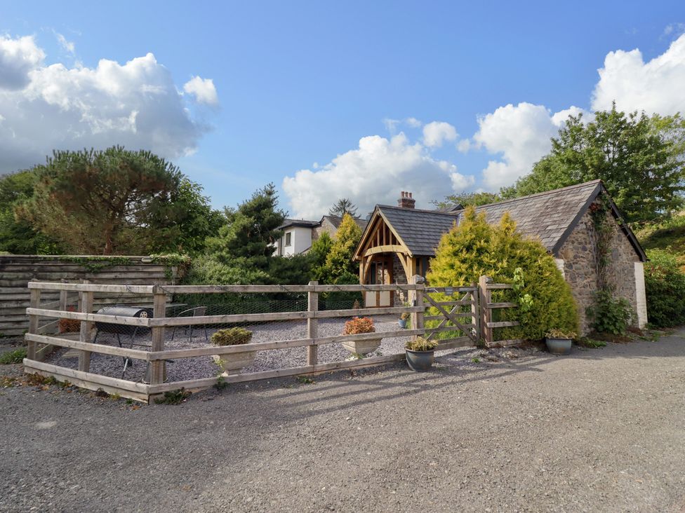 An outdoor view of a stone building with a wooden fence at The Talkhouse Cottage in Caersws