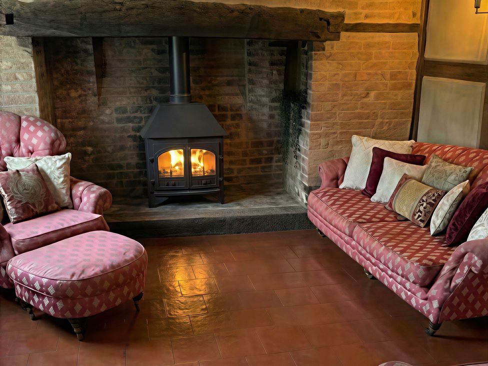 A living room with a fireplace, sofa, armchair, and ottoman at Lake Farm in Gloucester