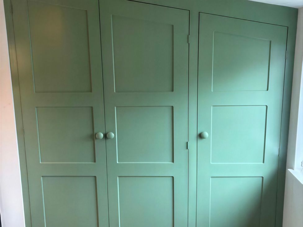 A green cupboard with doors and handles at Lake Farm in Gloucester