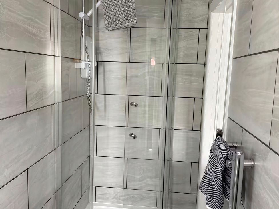 A bathroom with a shower and wall tiles at Lake Farm in Gloucester