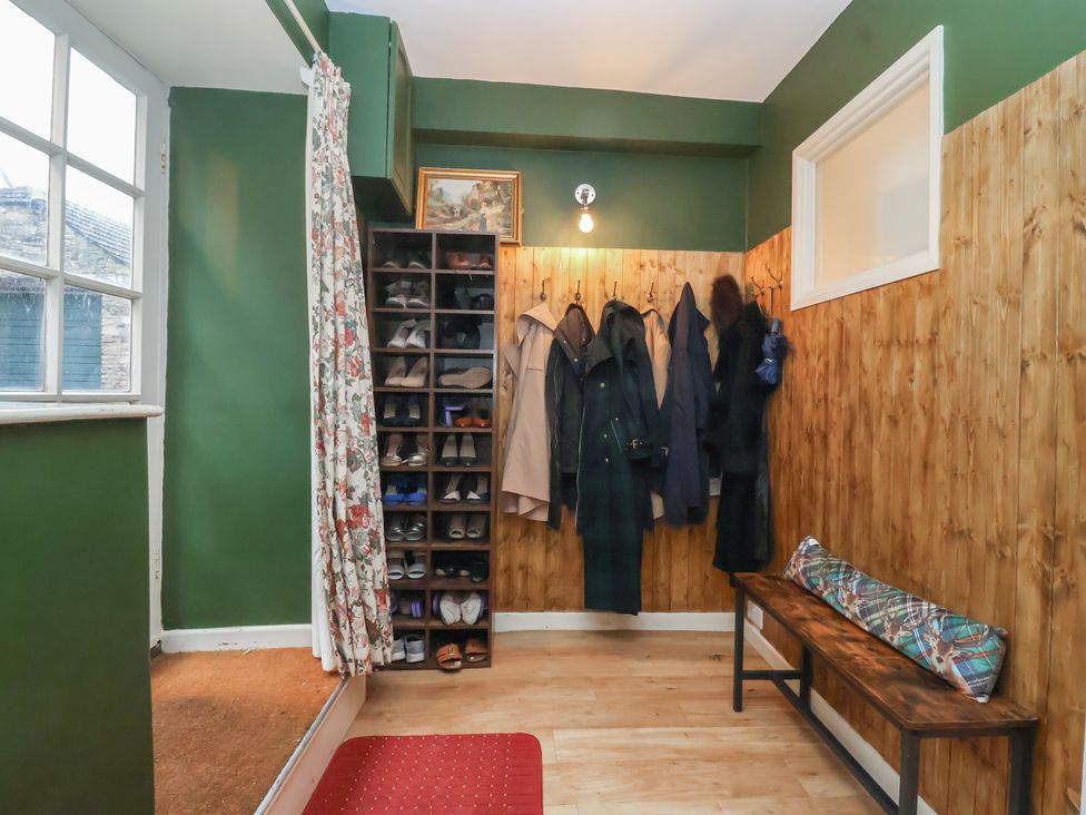 An entrance hall with coats hanging and a shoe rack at Waterloo Mill Cottage Wotton-Under-Edge
