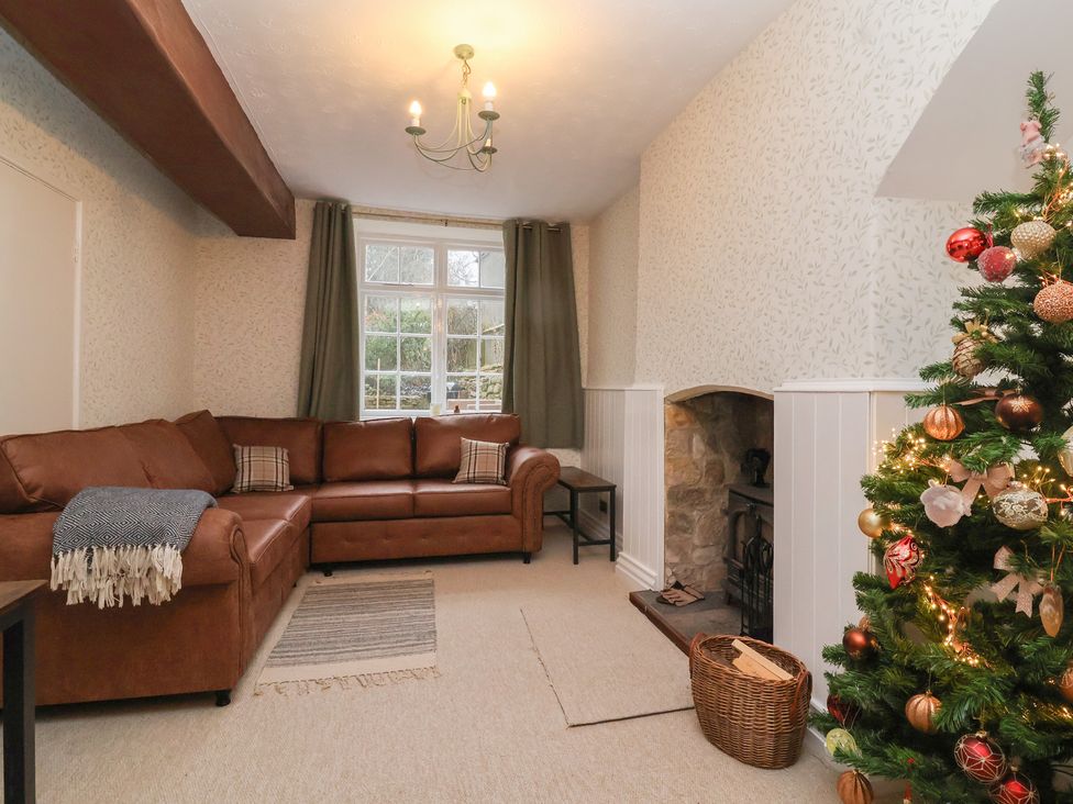 A living room with a sofa and a Christmas tree at Waterloo Mill Cottage in Wotton-Under-Edge