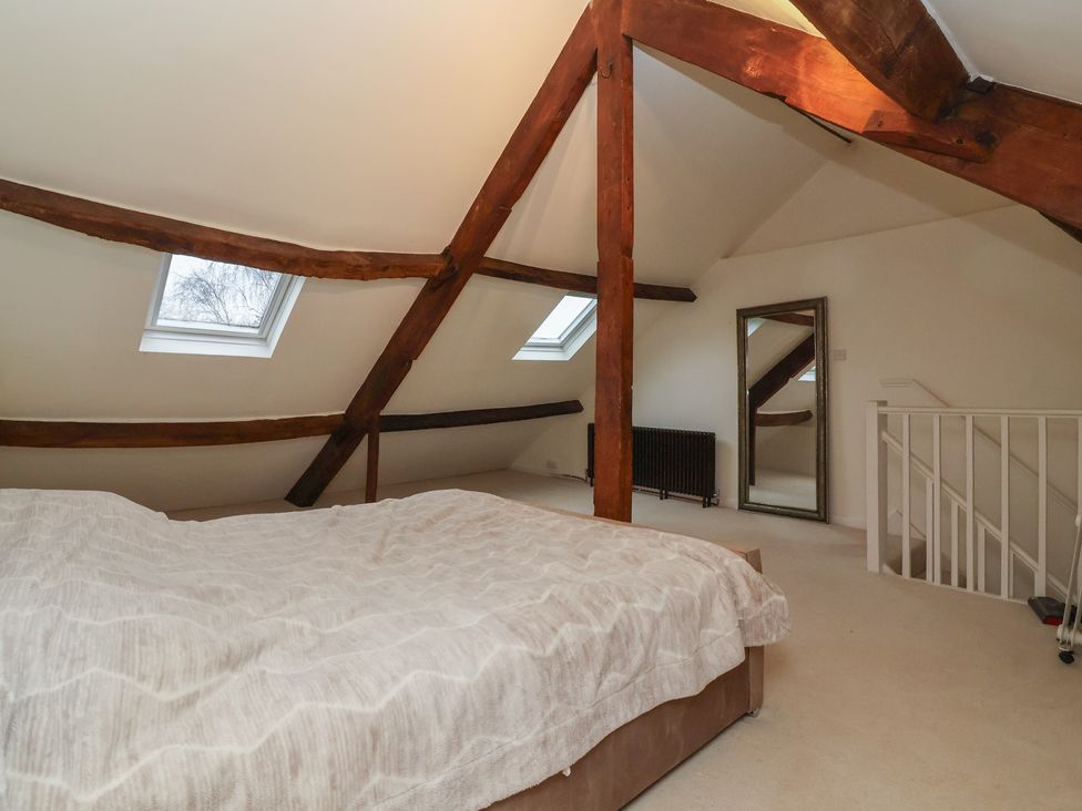 A bedroom with a bed, mirror and skylights at Waterloo Mill Cottage in Wotton-Under-Edge