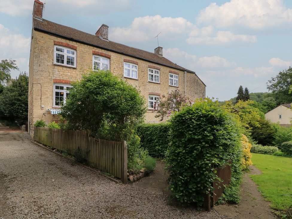 A house with windows and garden at Waterloo Mill Cottage in Wotton-Under-Edge