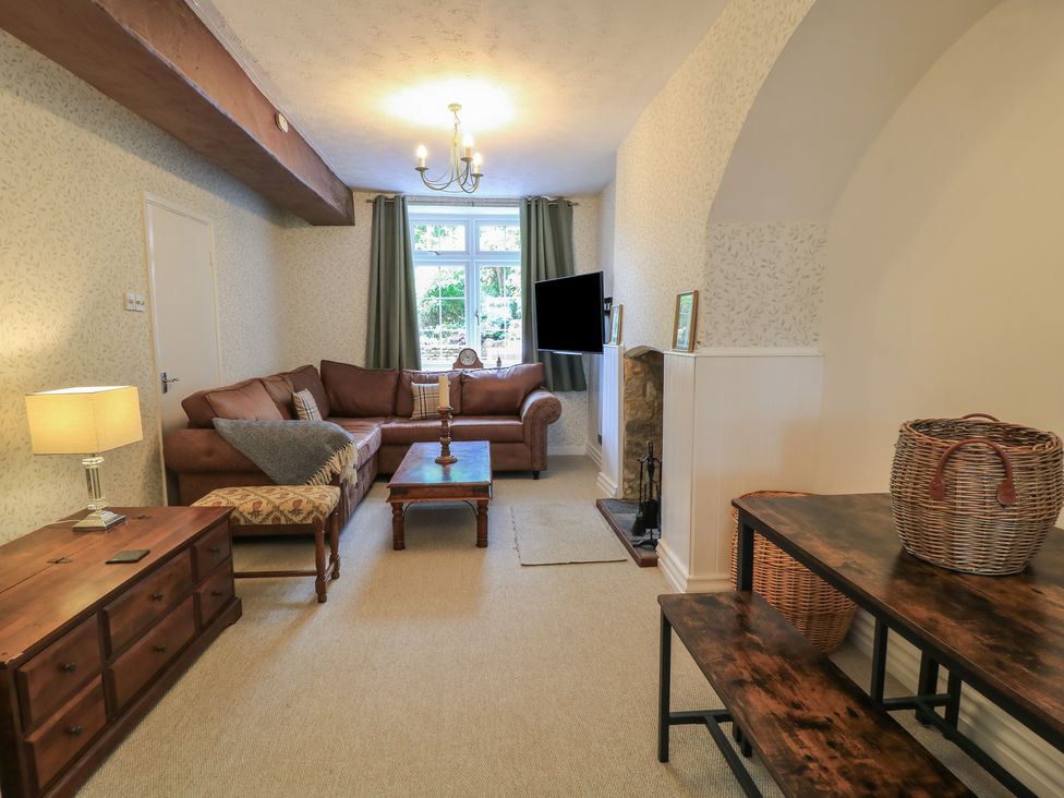 A living room with a sofa, coffee table, and television at Waterloo Mill Cottage in Wotton-Under-Edge