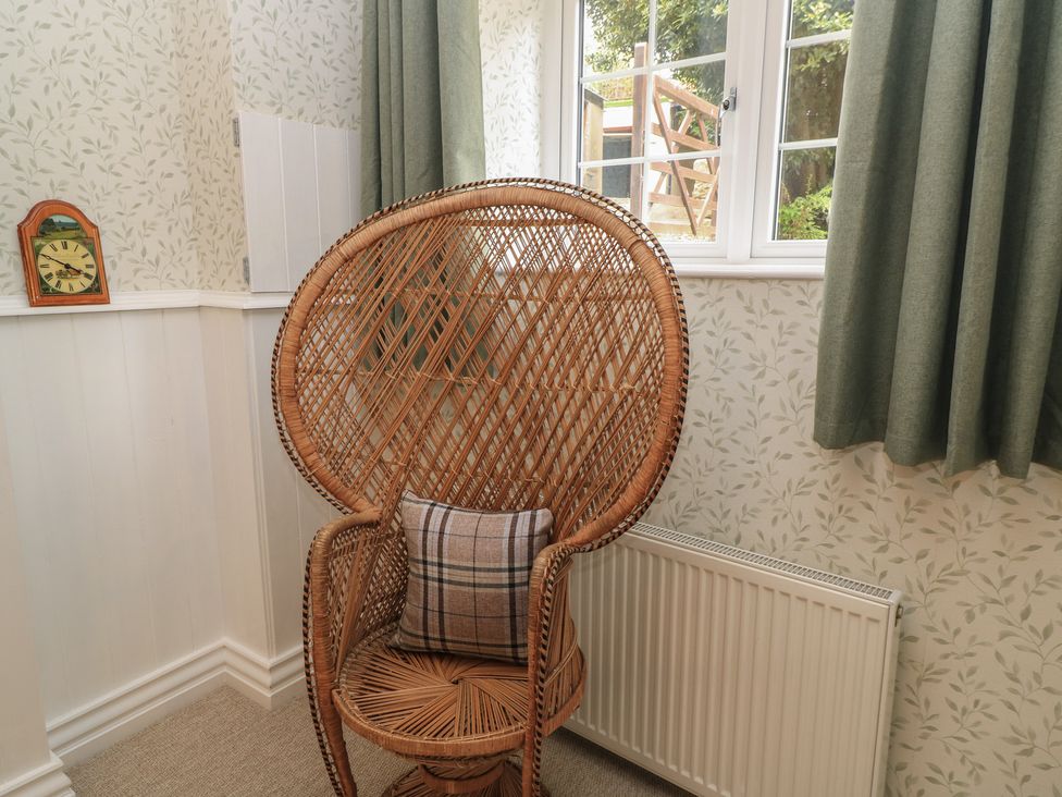 A snug with a rattan chair and clock at Waterloo Mill Cottage Wotton-Under-Edge