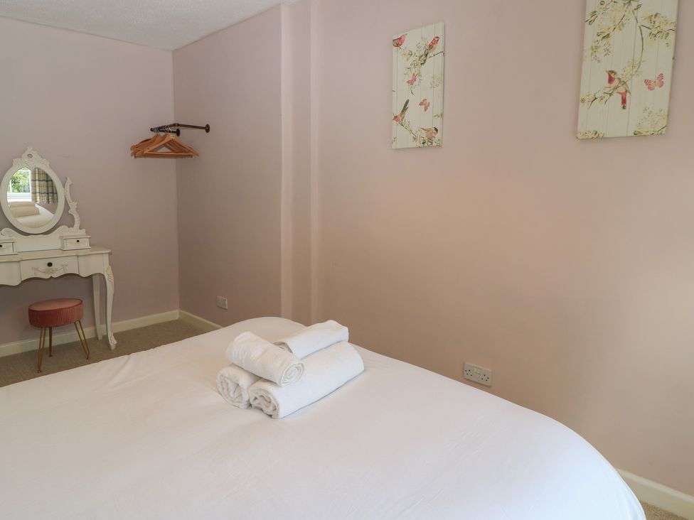 A bedroom with a bed and a vanity at Waterloo Mill Cottage in Wotton-Under-Edge