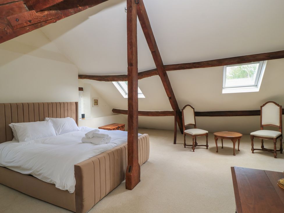 A bedroom with a bed and two chairs at Waterloo Mill Cottage Wotton-Under-Edge