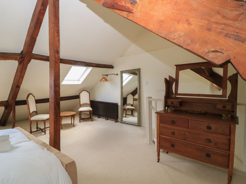 A bedroom with a dresser and mirror at Waterloo Mill Cottage in Wotton-Under-Edge