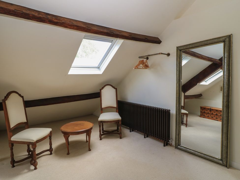 A bedroom with chairs and a mirror at Waterloo Mill Cottage in Wotton-Under-Edge